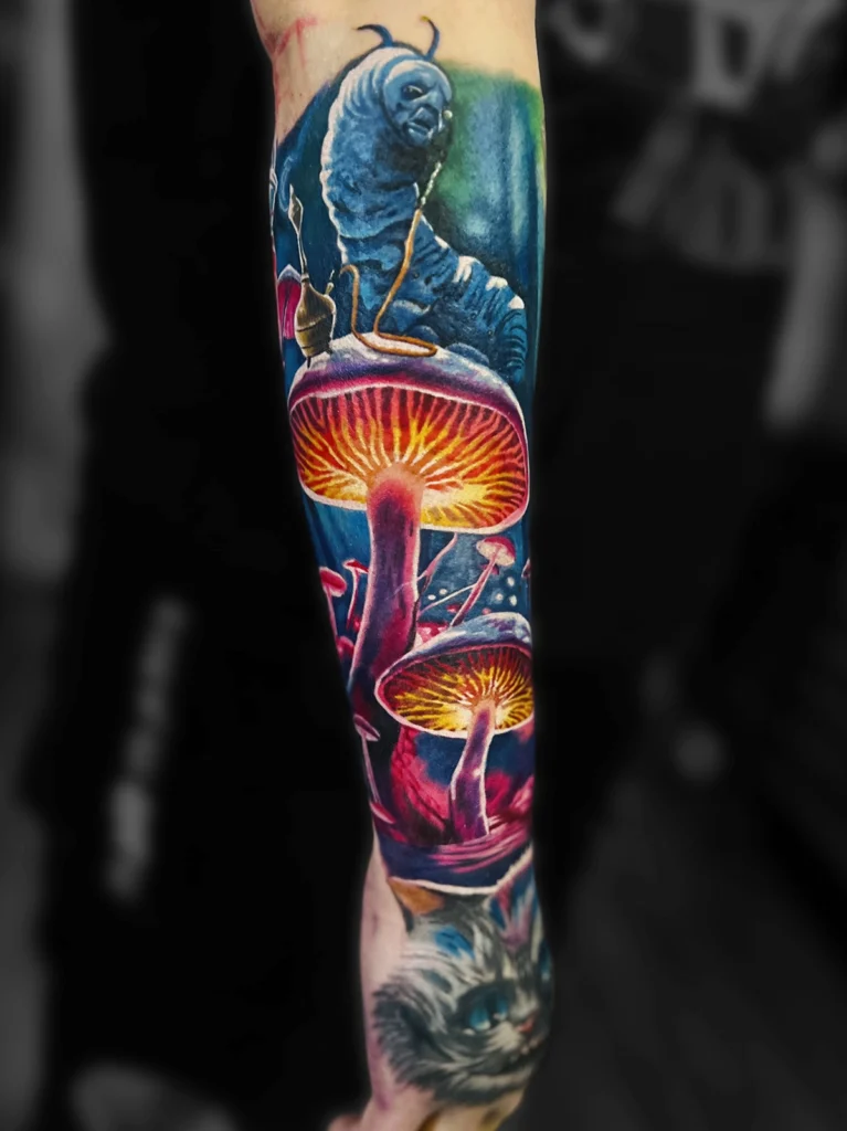 Kolorowy realistyczny tatuaż inspirowany Alicją w Krainie Czarów z Absolemem, Kotem z Cheshire i magicznymi grzybami wykonany przez Bartka w Studio Fortuna Tattoo w Warszawie.