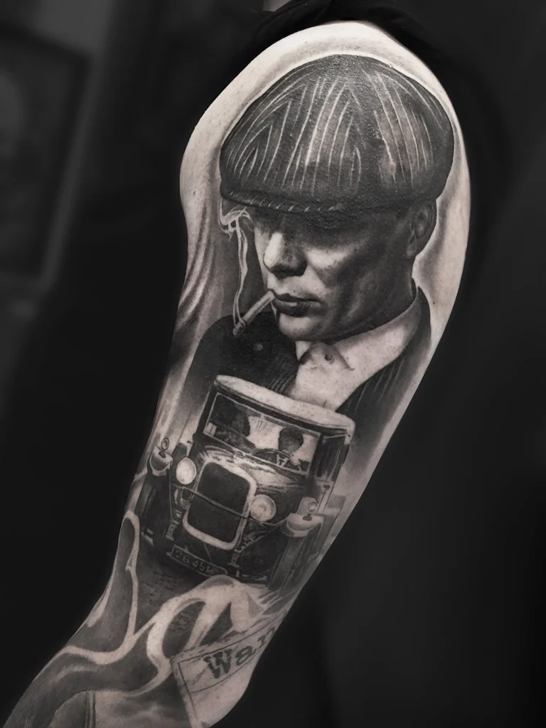 Realistyczny tatuaż z portretem Thomasa Shelby'ego oraz zabytkowym samochodem wykonany przez Bartka w Studio Fortuna Tattoo w Warszawie.