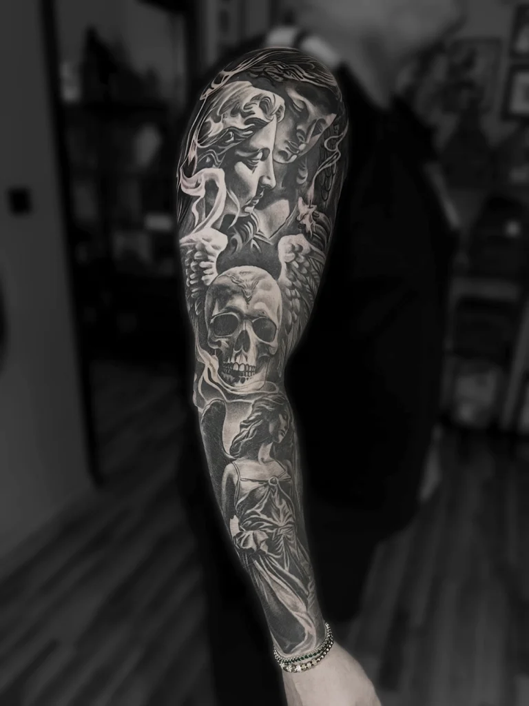 Tatuaż realistyczny black & grey przedstawiający anioła, czaszkę i kobiecy portret wykonany jako rękaw przez Bartka Fortunę w Warszawie.